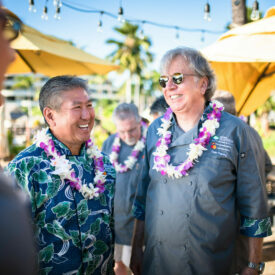 Chef Alan Wong & Chef Dean Fearing laughing outside with leis